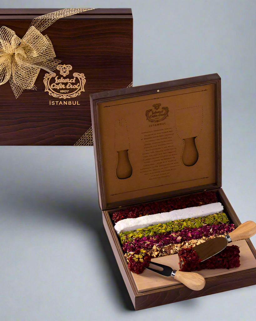 A wooden box of Special Turkish Delight with a knife, the box is open showing various snacks inside and a pair of utensils lie on the side.